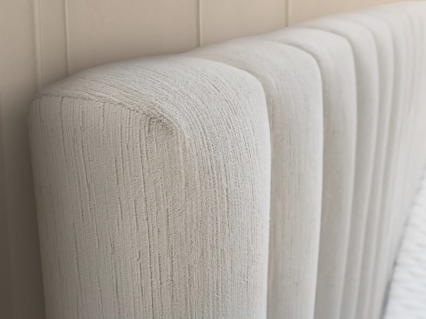 Velvet textured cream headboard against a beige wall