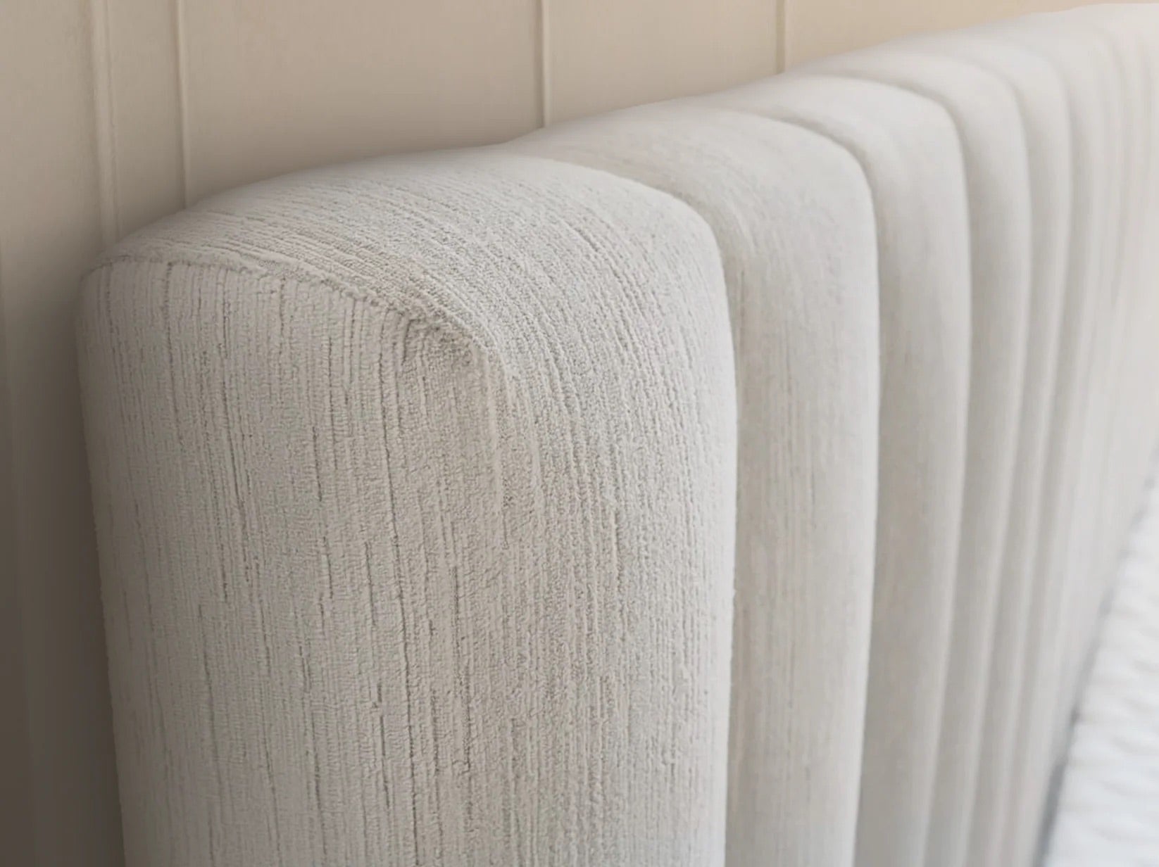 Velvet textured cream headboard against a beige wall