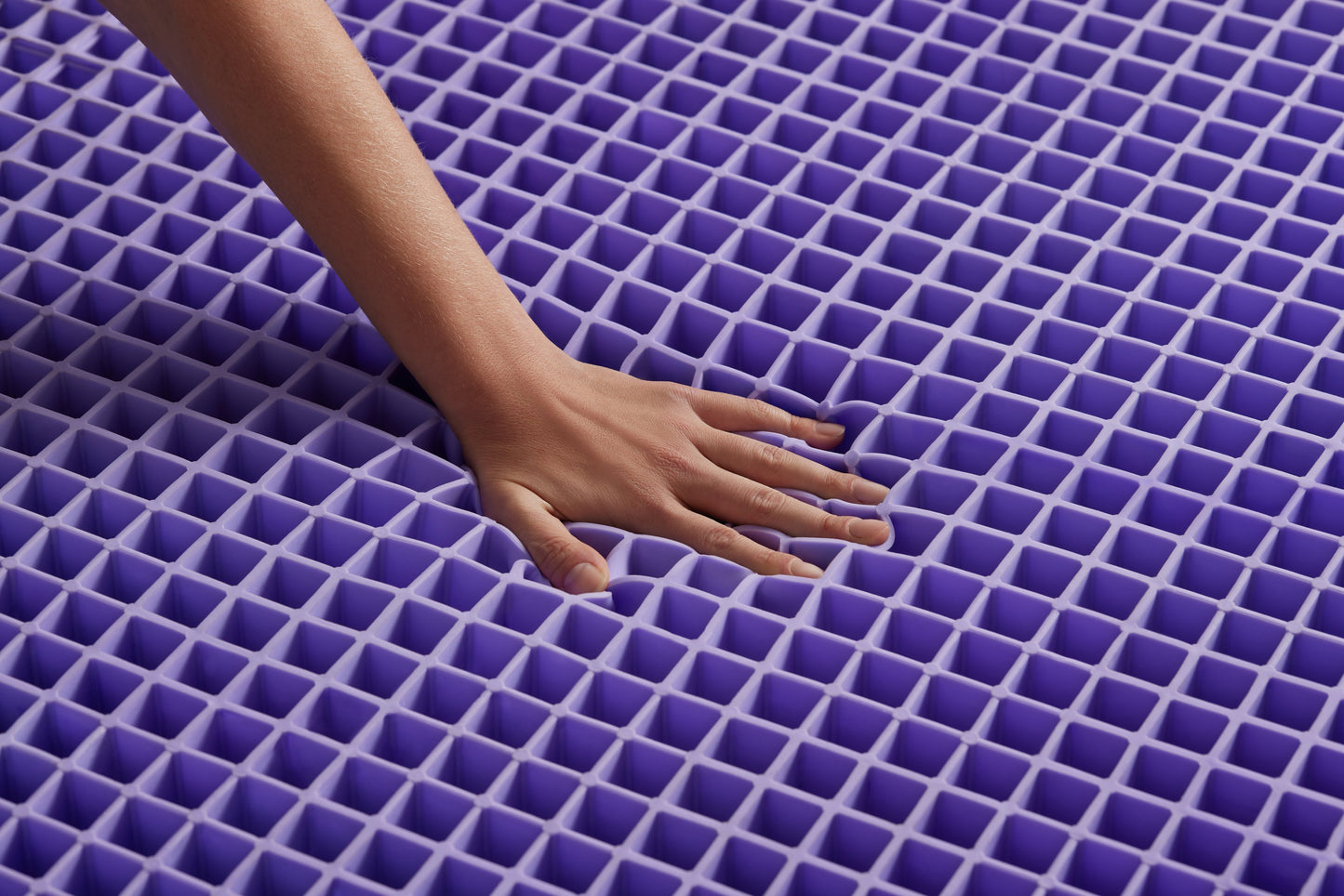 Hand touching a purple grid mattress later