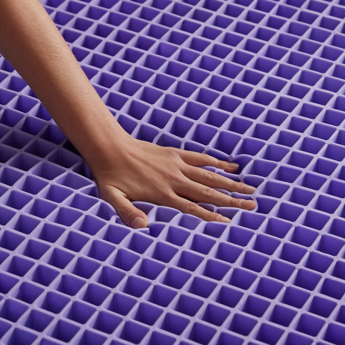 Hand touching a purple grid mattress later