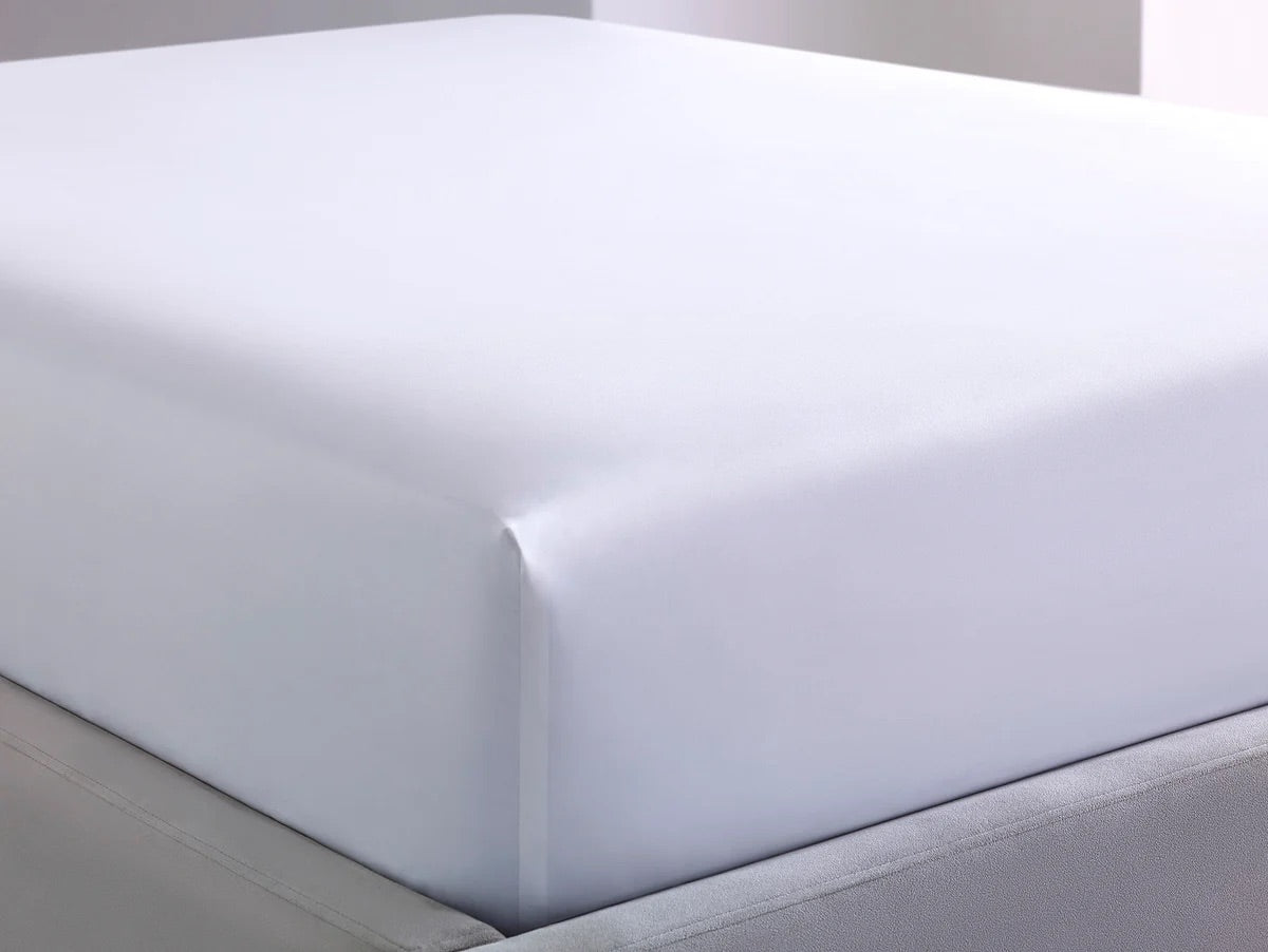 White mattress protector on a bed with a neutral background