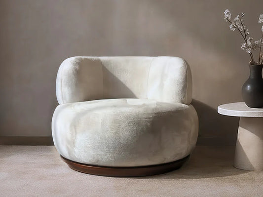 Modern beige armchair in a minimalistic room with a vase of flowers on a side table.