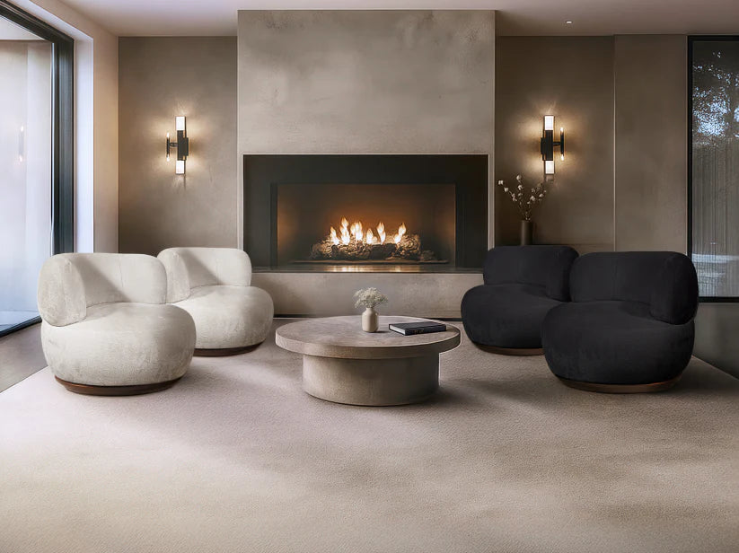 Modern living room with a fireplace, white and black chairs, and a round coffee table.