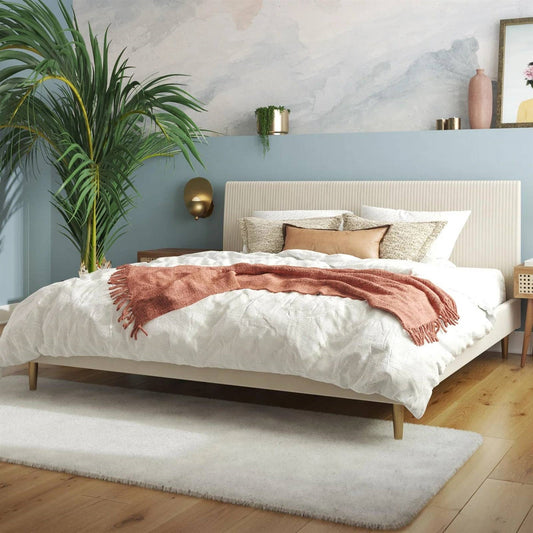 King size ivory velvet tufted platform bed with white bedding and a pink throw blanket in a bedroom setting.