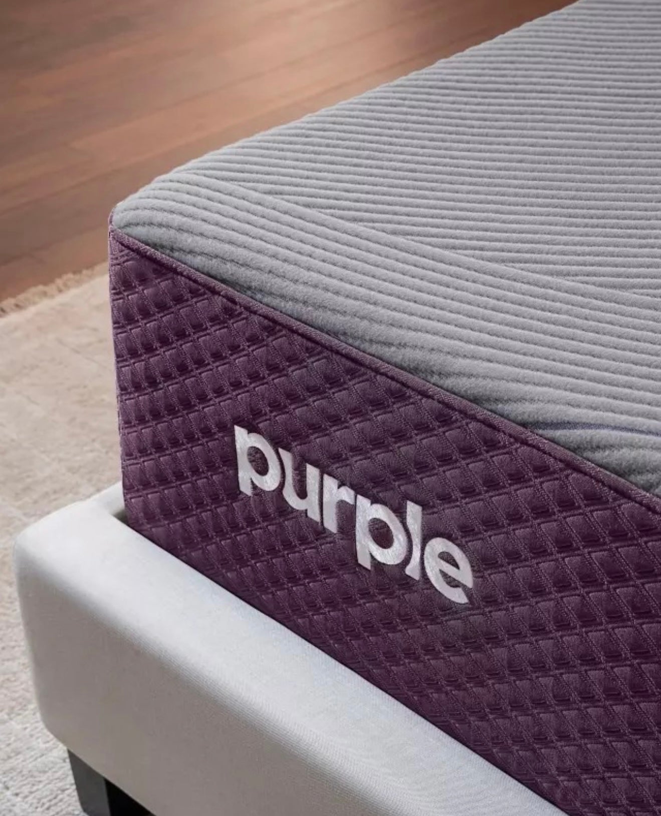 Purple mattress topper with brand logo on a bed