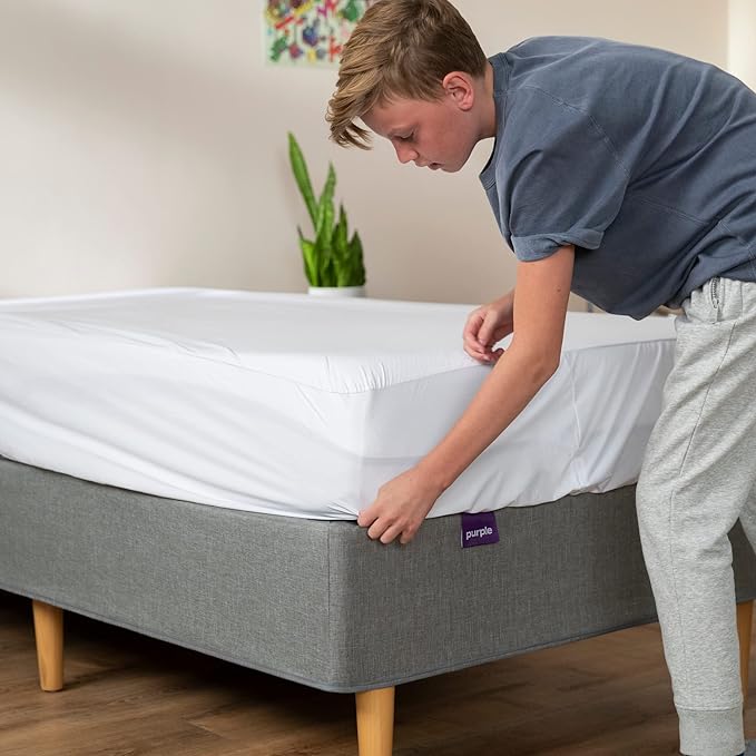 kid putting on purple brand mattress protector