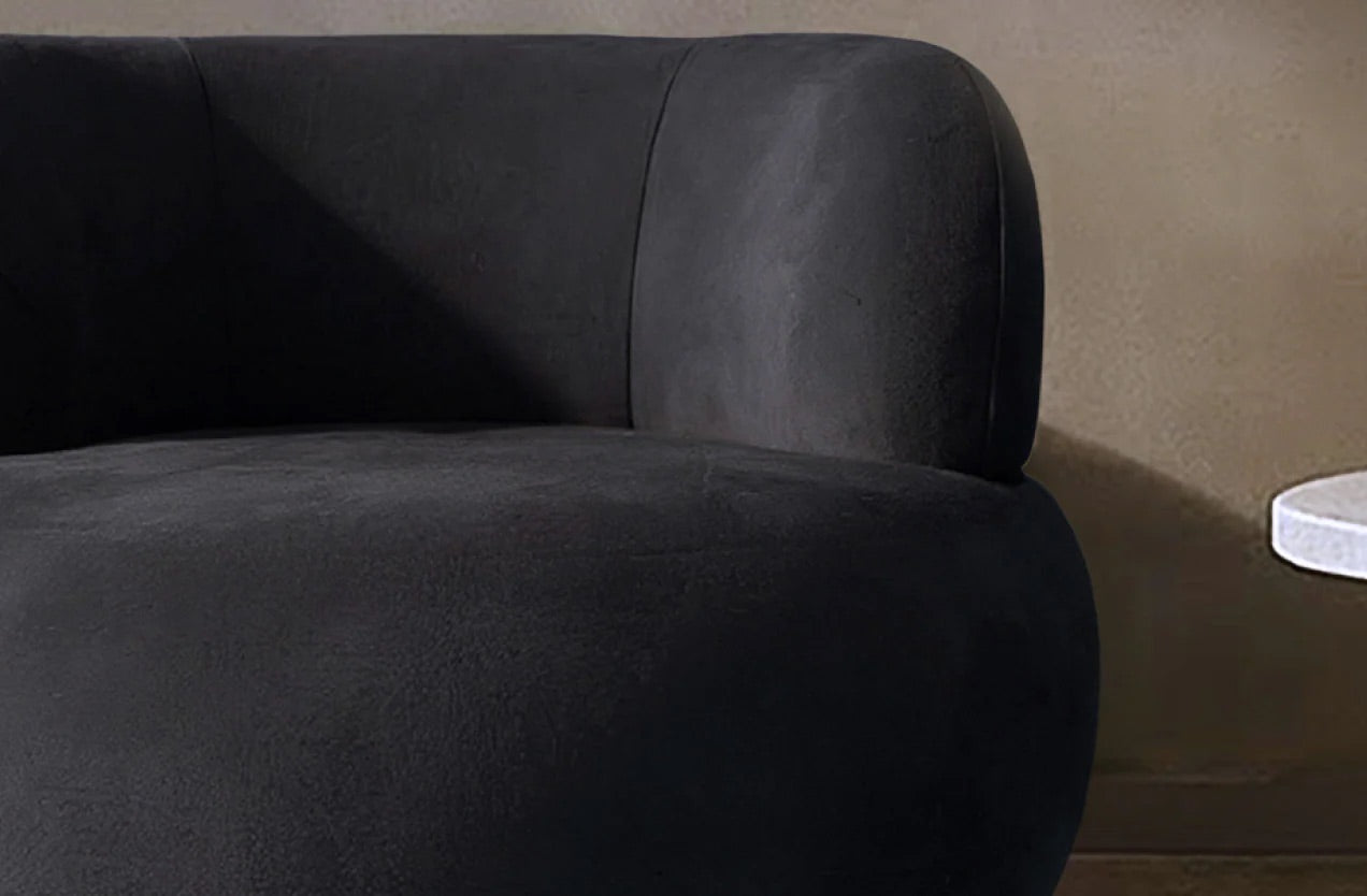 Dark gray luxury accent chair against a brown wall