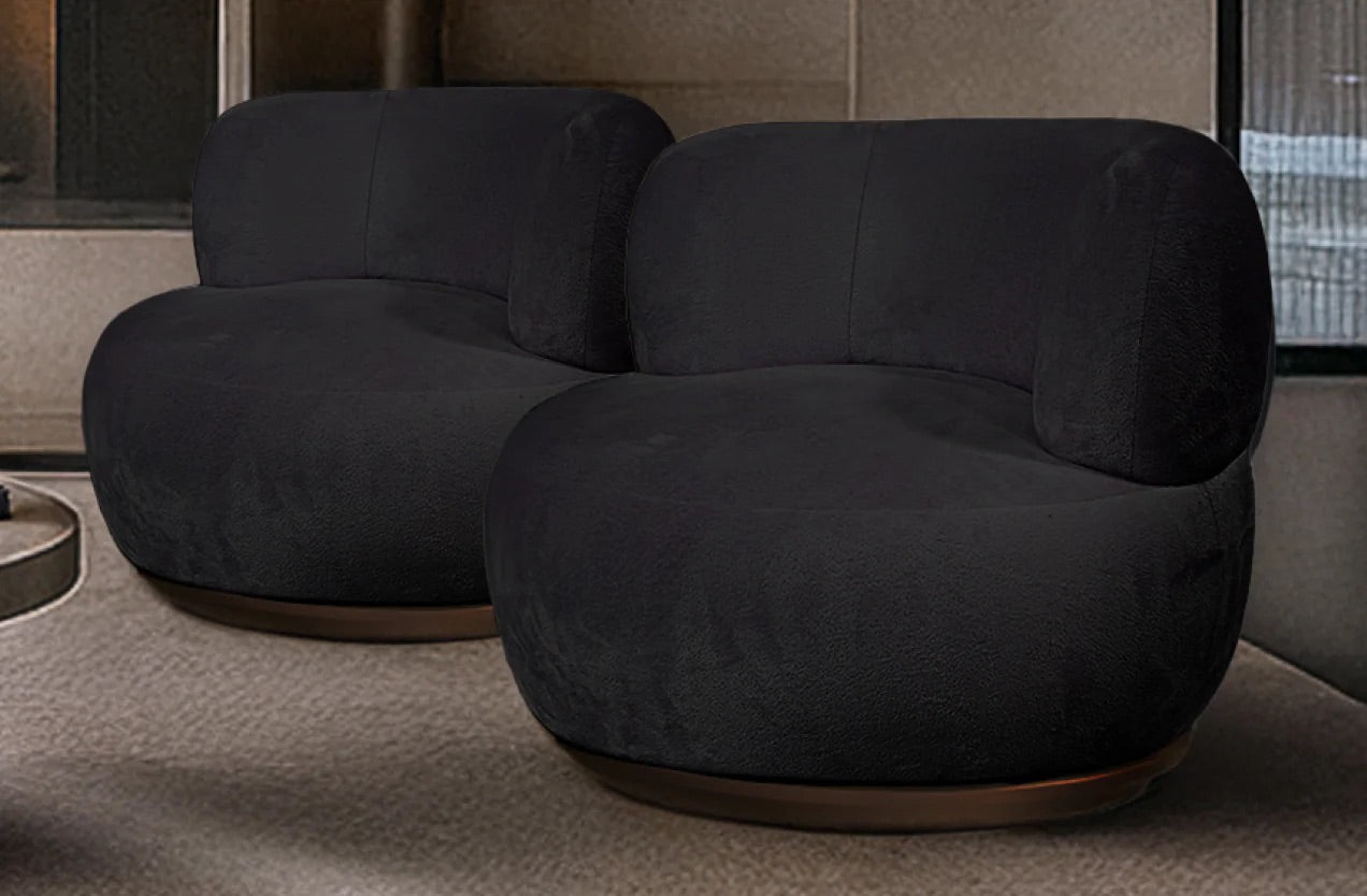 Two dark gray armchairs in a room with a neutral color scheme.