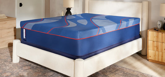 Blue mattress with red accents on a white bed frame in a bedroom setting.