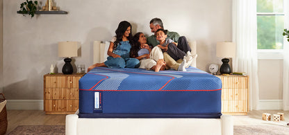 Family sitting on a mattress in a bedroom setting