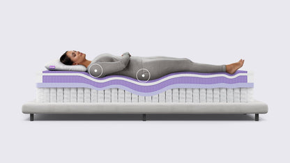 Woman lying on a mattress with a cross-sectional view showing its layers.