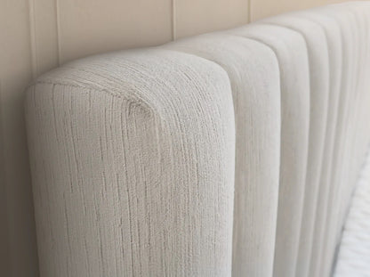 Velvet textured cream headboard against a beige wall