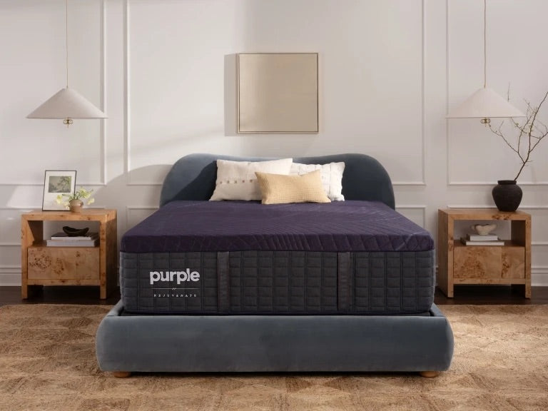 Purple mattress on a bed in a bedroom setting with wooden nightstands and decor.