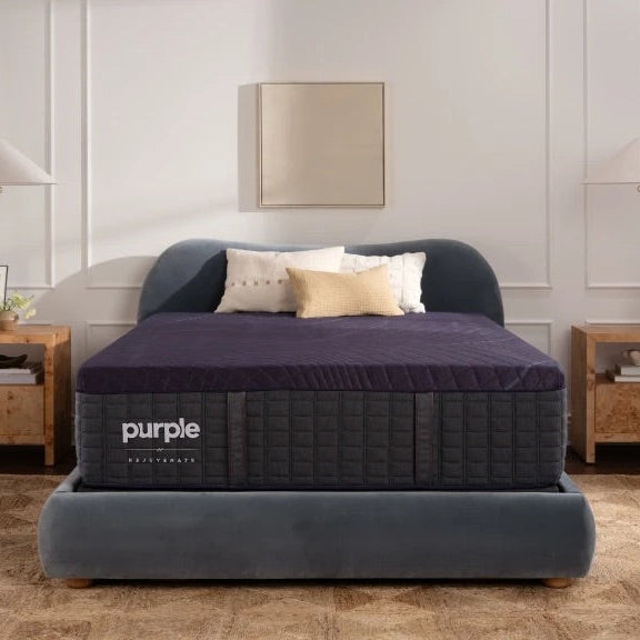 Purple mattress on a bed in a bedroom setting with wooden nightstands and decor.