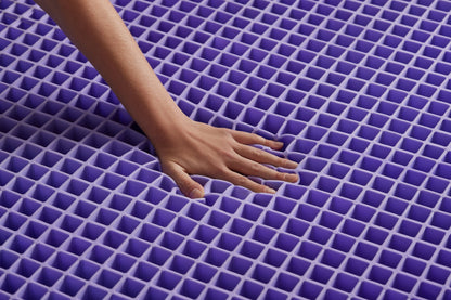 Hand touching a purple grid mattress later