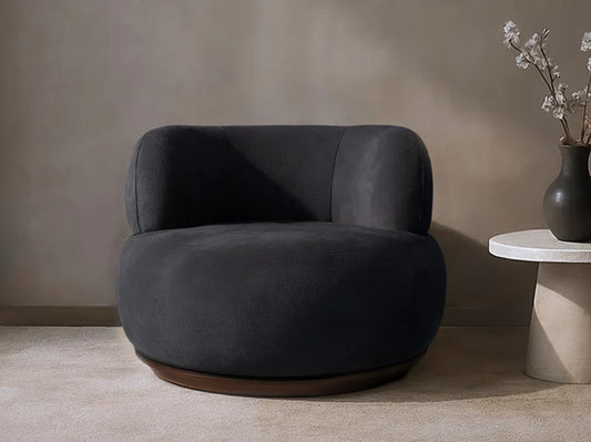 Dark gray armchair in a minimalistic room with a vase on a side table.