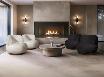 Modern living room with a fireplace, white and black chairs, and a round coffee table.
