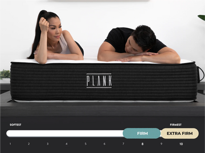 Two people lying on a PLANK mattress with a scale indicating firmness levels.