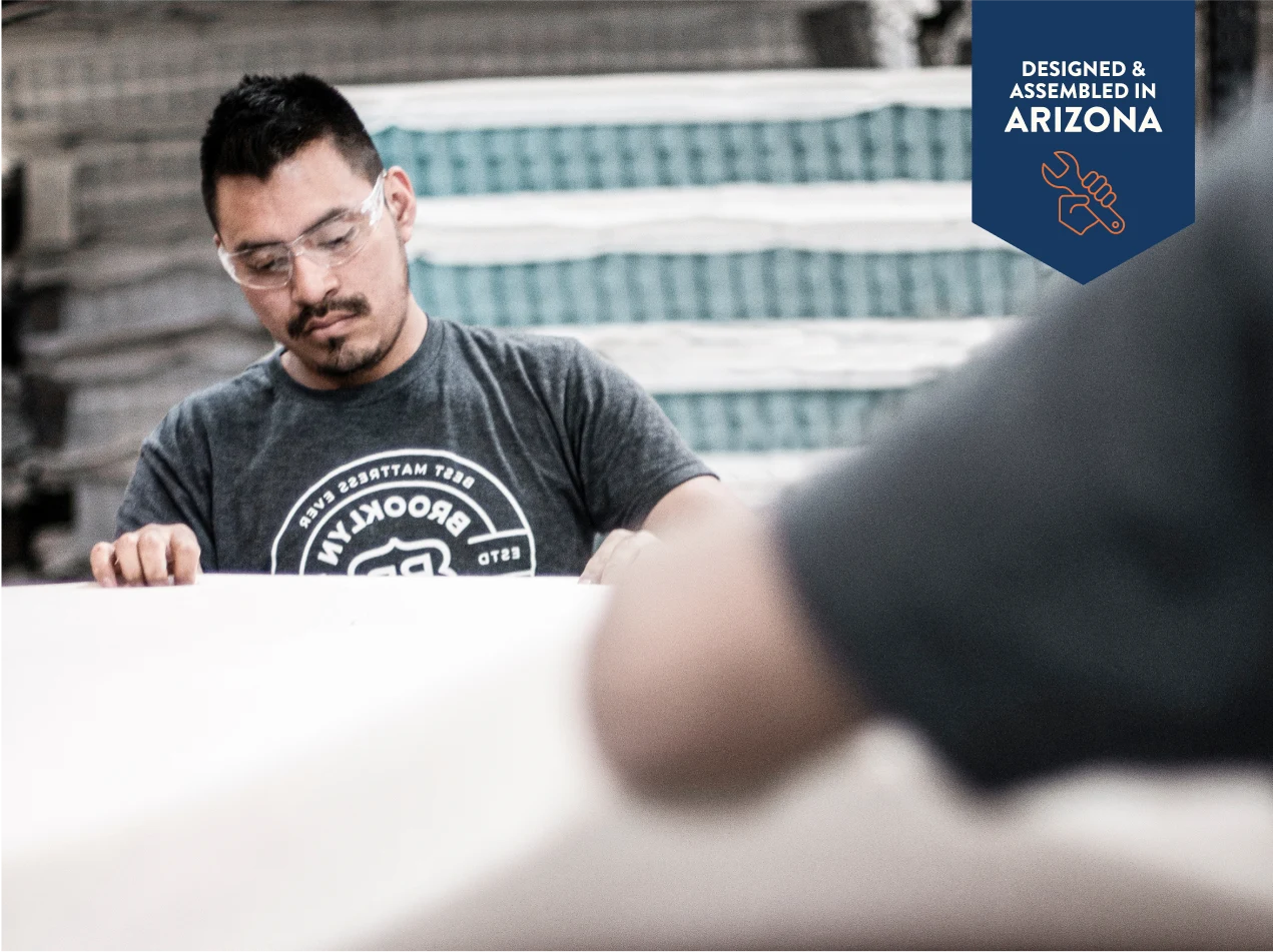 Person wearing a gray t-shirt with a logo, sitting at a table with another person whose face is blurred.