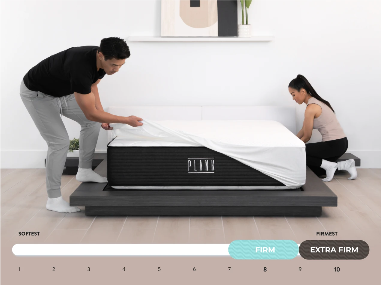 Two people adjusting a PLANK mattress on a white background