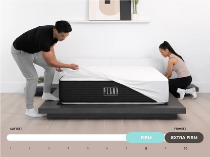 Two people adjusting a PLANK mattress on a white background