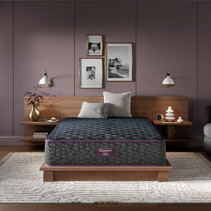 Mattress on a wooden bed frame in a bedroom setting with purple walls and decor.