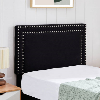 Black upholstered headboard with nailhead trim on a bed in a bedroom setting.