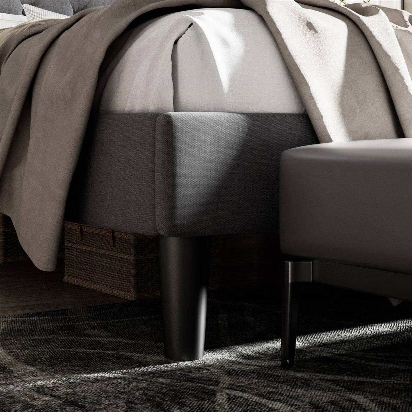 King size black upholstered bed with a textured blanket and wicker basket on a dark rug.