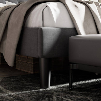 King size black upholstered bed with a textured blanket and wicker basket on a dark rug.