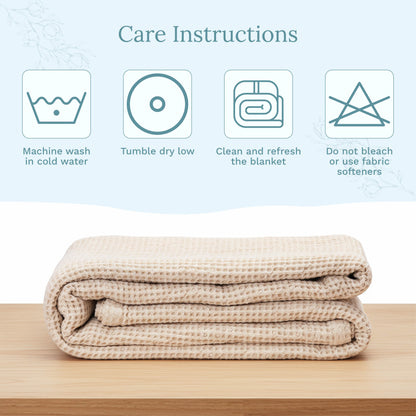 Folded beige blanket on a wooden surface with care instructions displayed above.