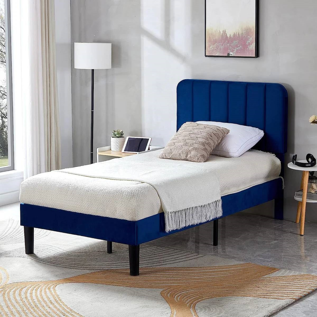 Blue twin upholstered platform bed frame with white bedding in a modern bedroom setting.