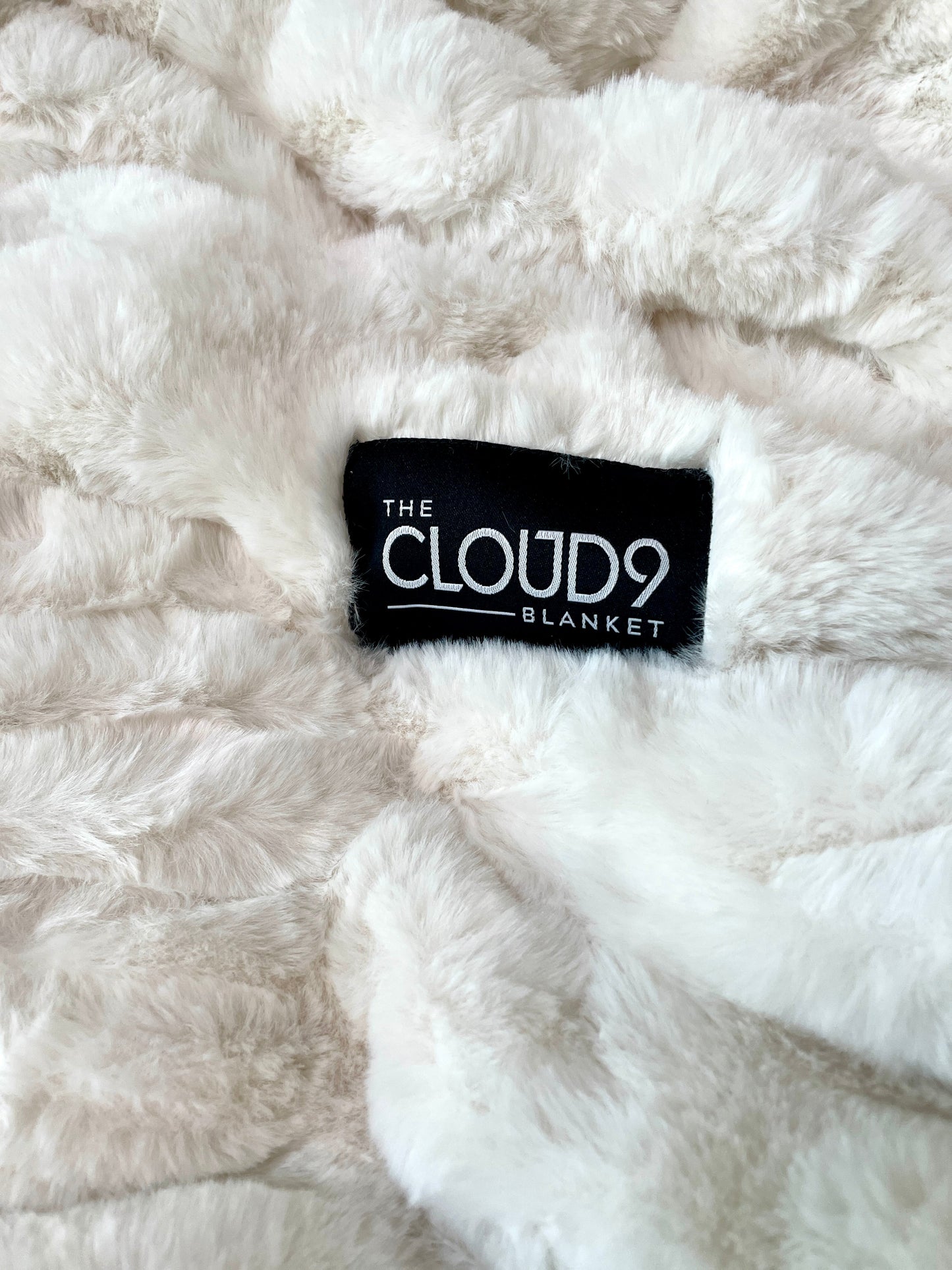 Close-up of a fluffy white blanket with 'The Cloud9 Blanket' label.