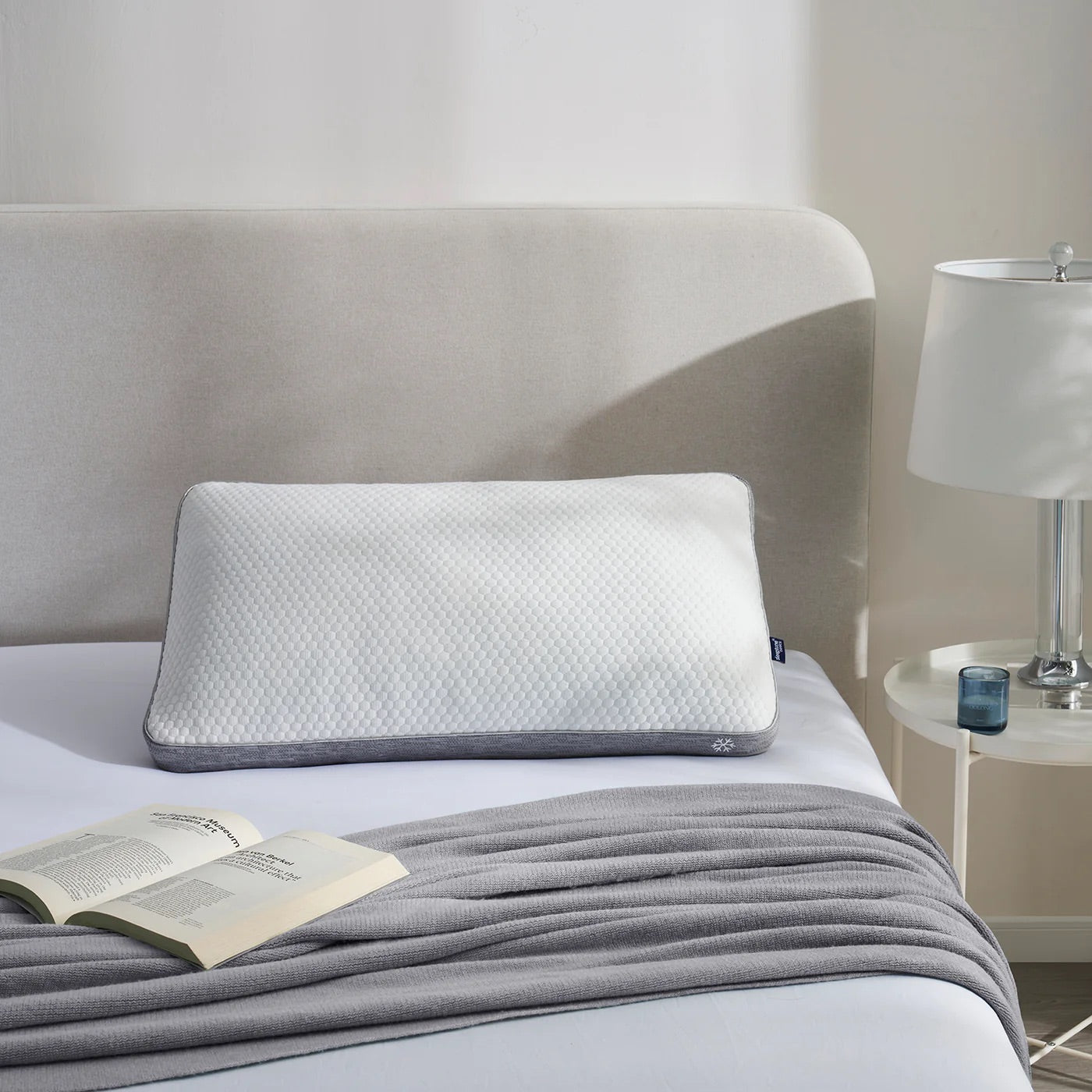 Cooling pillow on a bed with a nightstand and lamp in a bedroom setting