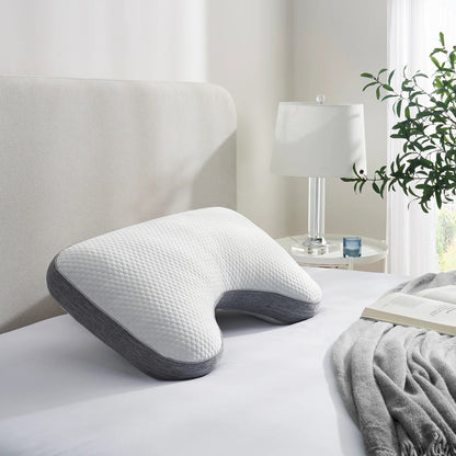 Cooling pillow on a bed in a bedroom setting with a lamp and plant in the background