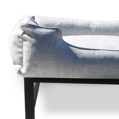 Gray upholstered dog bed on a black metal frame with a white background
