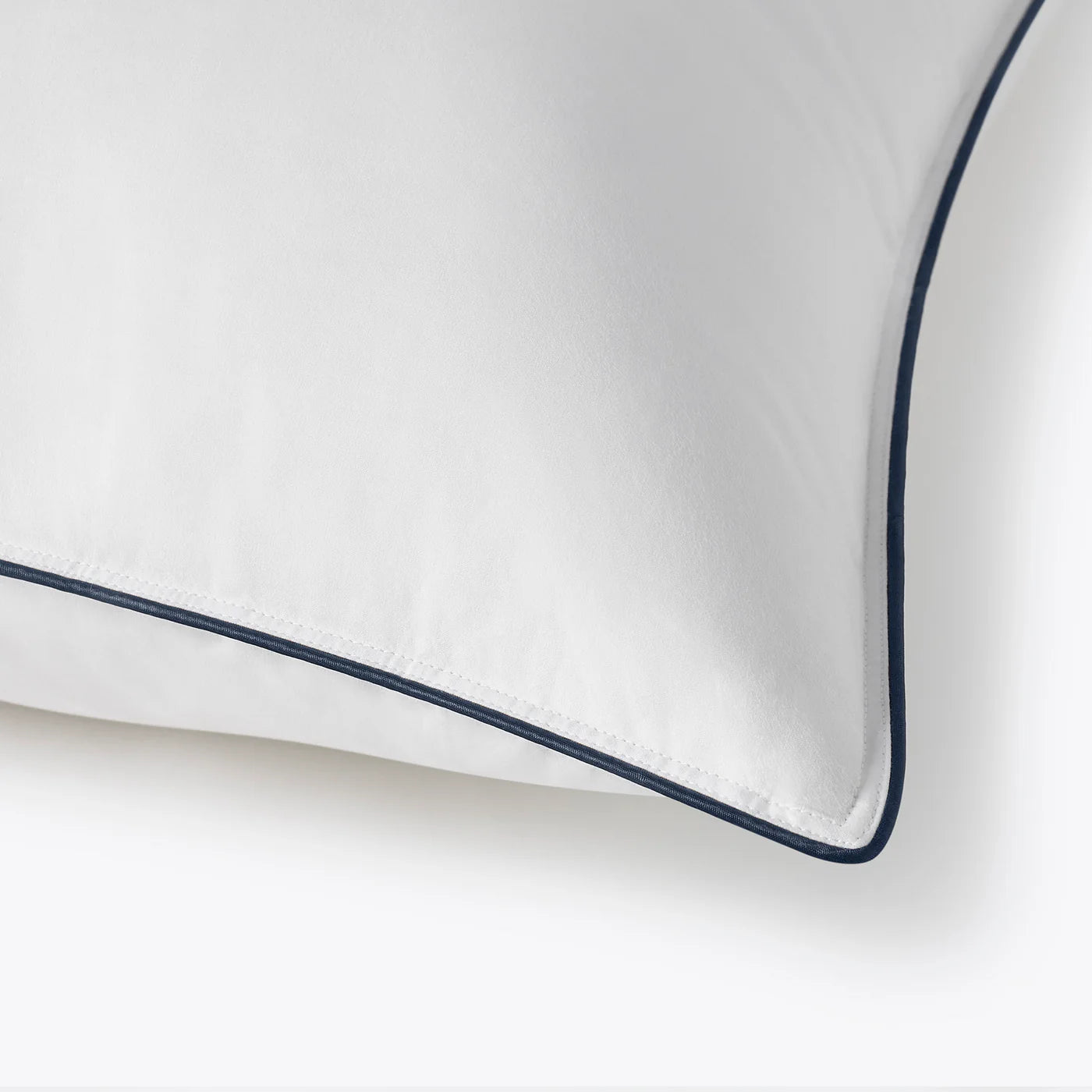 White pillow with navy blue piping on a white background