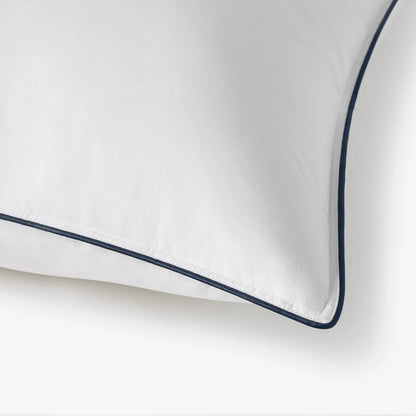 White pillow with navy blue piping on a white background
