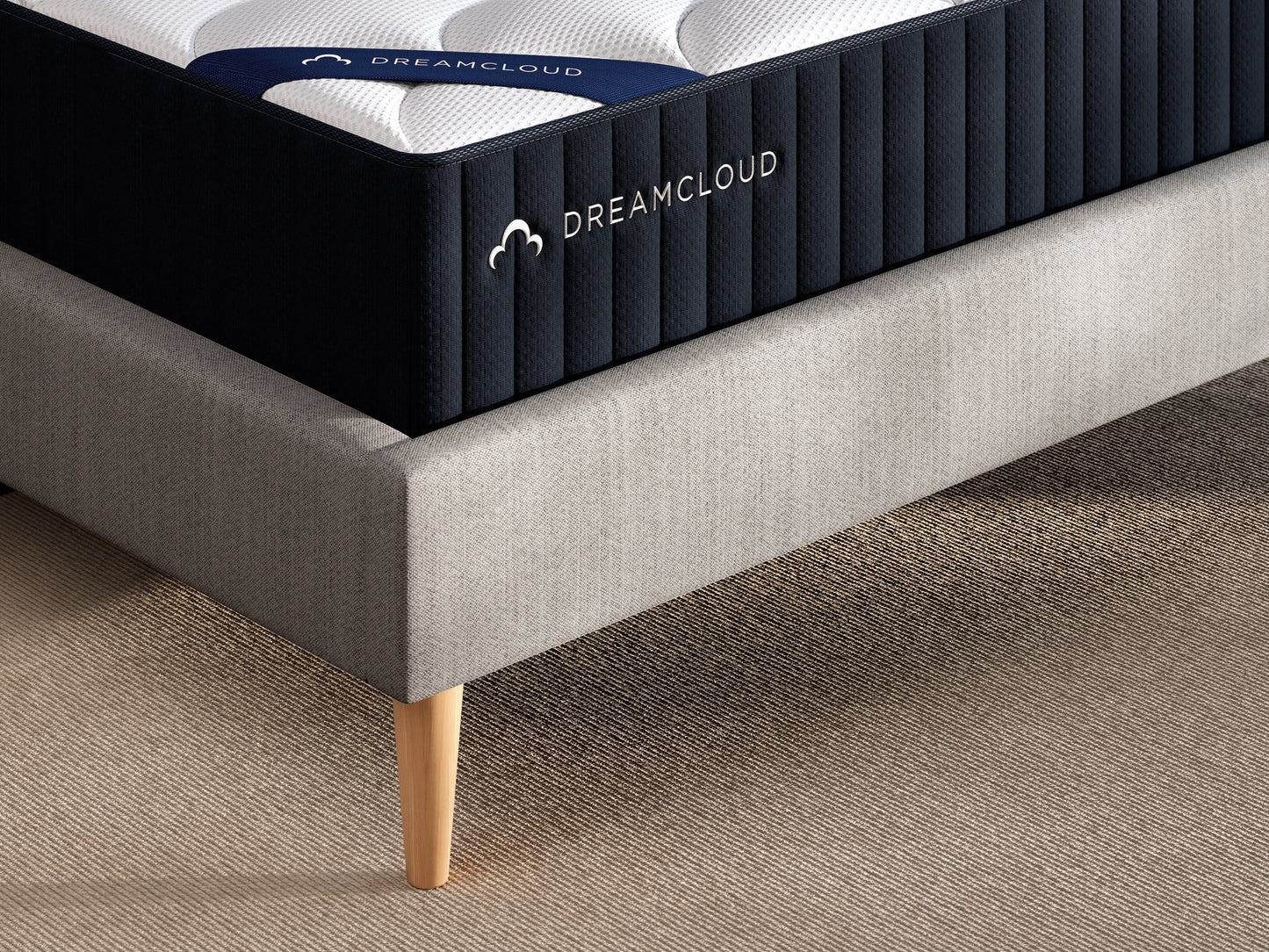 DreamCloud mattress on a bed frame with a neutral background