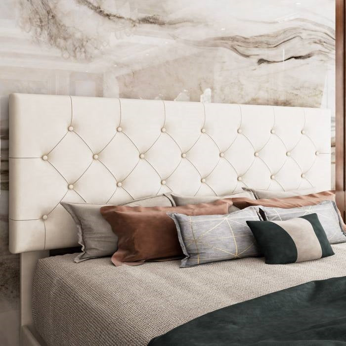 Full size bed with white tufted headboard and decorative pillows against a marble wall.