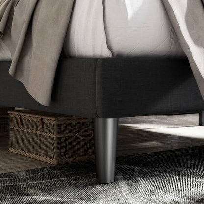 Close-up of a bed with dark gray bedding and a metal bed frame.