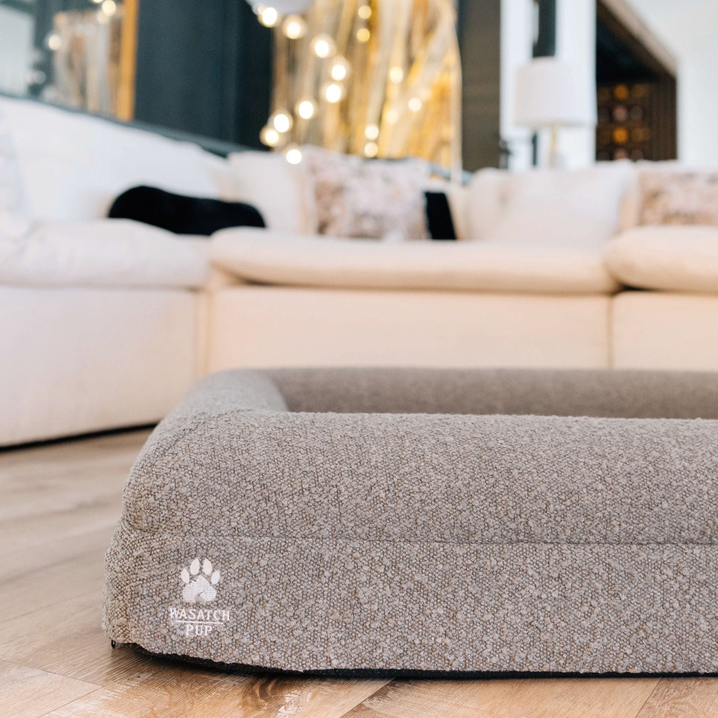 Gray pet bed with a brand logo in a living room setting