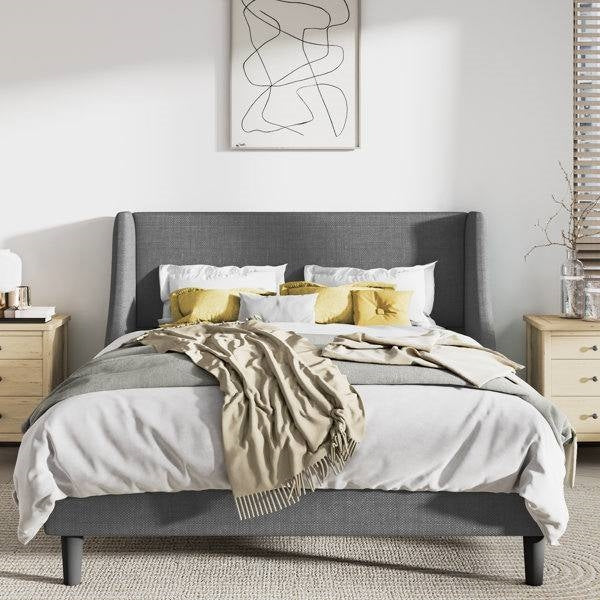 King size gray wingback linen upholstered bed with white bedding and yellow pillows in a bedroom setting.