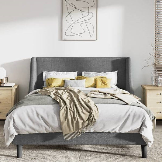 King size gray wingback linen upholstered bed with white bedding and yellow pillows in a bedroom setting.