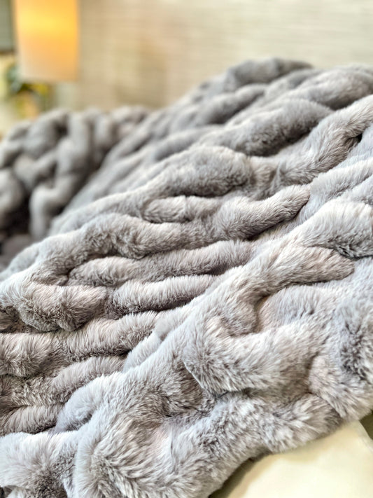 Close-up of a textured gray blanket on a surface with a blurred background