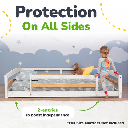 Children's bed with safety rail, child standing on the floor, and teddy bear on the bed.