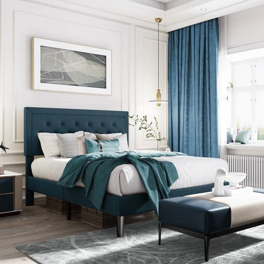 Modern bedroom with King size blue bed and matching ottoman, white walls, and large window.