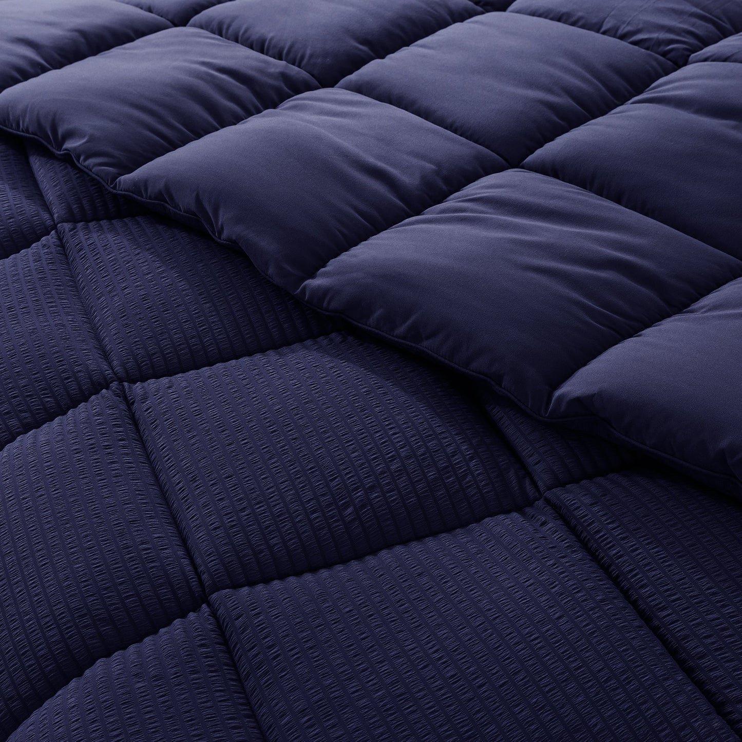Navy blue quilted comforter with a diamond pattern on a bed.