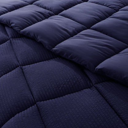 Navy blue quilted comforter with a diamond pattern on a bed.
