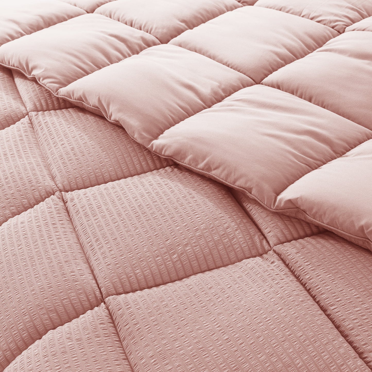 Close-up of a pink quilted comforter with a soft texture.