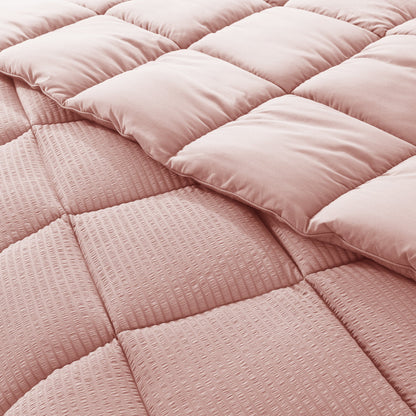 Close-up of a pink quilted comforter with a soft texture.